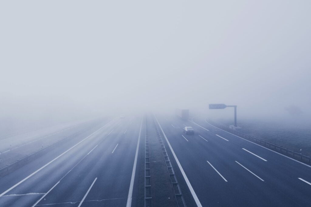 Coches conduciendo en una autopista en condiciones de niebla espesa